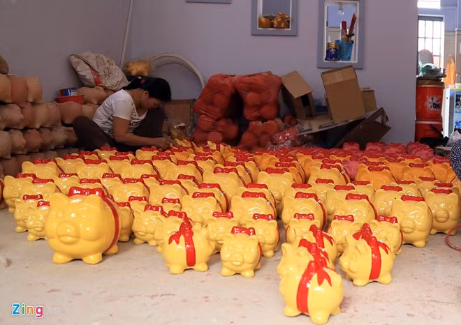 Một thợ gốm đang phủ sơn cho sản phẩm heo đất tiết kiệm. Chị cho biết, công việc không mấy vất vả nên tiền công ngày thường chỉ 3-4 triệu đồng mỗi tháng. "Tết là dịp các chủ lò cần lượng hàng lớn đáp ứng thị trường nên phần công việc nhiều hơn. Điều đó đồng nghĩa với việc thu nhập được cải thiện", thợ gốm cho biết.