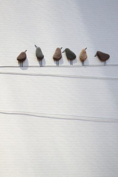 Trang trí tường. Chọn những hòn cuội nhỏ có kích thước tương đồng nhau và dán nó trên tường theo một đường thẳng. Sau đó vẽ thêm đôi chân và mỏ chim, giăng thêm dây nữa là bạn đã có một hàng những chú chim đậu trên dây điện hết sức dễ thương.