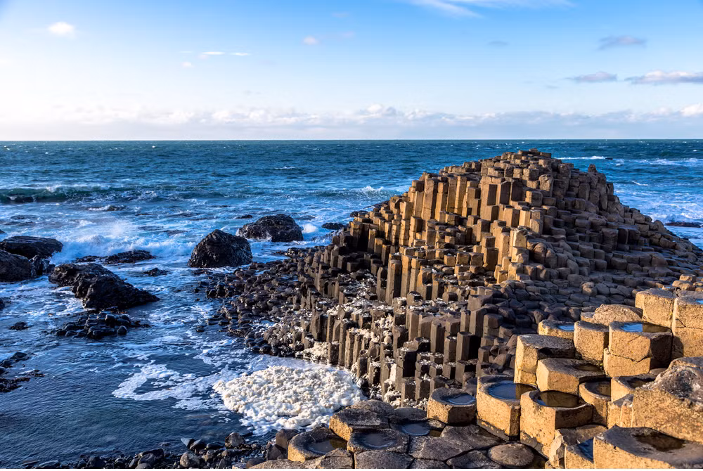 Giant's Causeway nằm ở Ireland gây ấn tượng với du khách với khoảng 40.000 cột đá ấn tượng. Chúng được tạo thành từ một vụ phun trào núi lửa cổ xưa. Những cột đá này trông giống như một con đường của người khổng lồ.