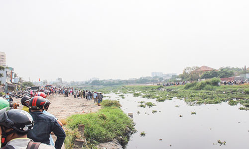 Nhiều người hiếu kỳ vây kín hai bên dòng kênh để theo dõi.