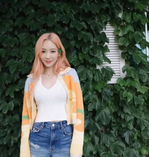 Taeyeon mix áo dệt kim màu trắng với short jeans rách cá tính, mẫu áo cardigan màu sắc khoác ngoài là item từng được Lisa tạo trend trước đó nhưng vẫn mang nét cá tính riêng.
