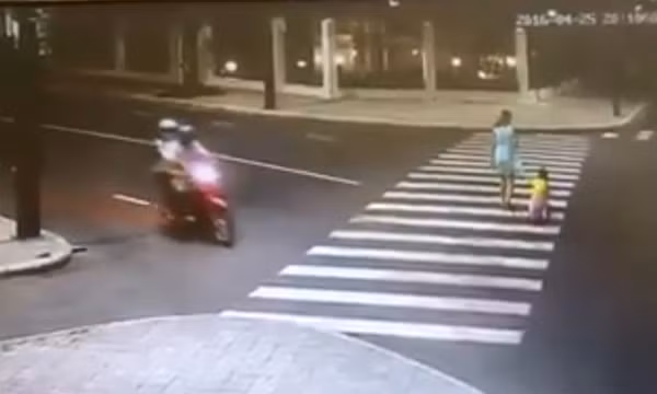 Lái xe máy ngoái cổ ngắm cô gái mặc váy đang qua đường. Ảnh cắt từ clip.