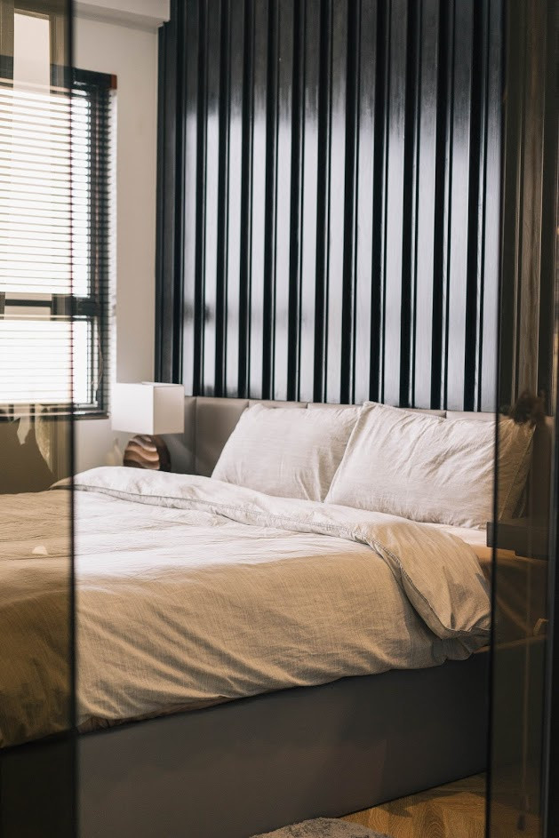 Phòng ngủ tách biệt bởi lớp kính tối màu với những gam màu trầm, thể hiện tính cách của chủ nhà.