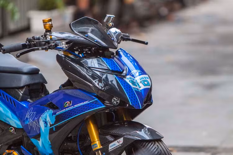 Sử dụng phuộc USD Ohlins lấy từ Ducati 1199 Panigale, tuy nhiên bản độ này có điểm độc đáo hơn nhiều chiếc Exciter 150 khác tại Việt Nam đó là không cắt phuộc do sử dụng tay lái trần. Đèn pha của chiếc xe đã được thay thế bằng cặp đèn LED L4 nằm ở vị trí đèn demi nguyên bản trên Exciter, trong khi đèn xi-nhan của xe là loại Motogadget nằm trên đầu xe.