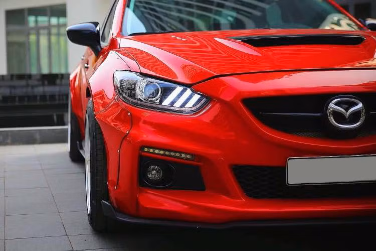 Nằm trên nắp ca-pô của xe nay cũng là các khe hút gió và tản nhiệt mới, giúp động cơ lưu thông khí nóng hiệu quả hơn. Chưa dừng lại ở đèn LED định vị trên cản trước theo mẫu của AutoExe, chiếc Mazda 6 còn có cụm đèn pha trước chế chóa cực độc đáo với các dải LED sáng theo phong cách Ford Mustang và đèn pha dạng thấu kính projector.