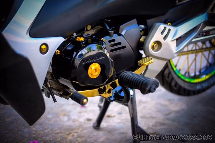 Khối động cơ nguyên bản của Wave S cũng được trang trí lại đầy bắt mắt với dàn ốc kiểng màu vàng, cần số sơn màu chrome vàng kim loại, "mang cá" xẻ rãnh, ốp bưởng côn Takegawa và nắp ốc dầu Proti. Ở phía sau xe là dàn để chân cho người ngồi sau "giò gà" được lấy từ Honda Wave Nice Thái Lan - chi tiết hiếm khi vắng mặt trên các bản độ kiểng.