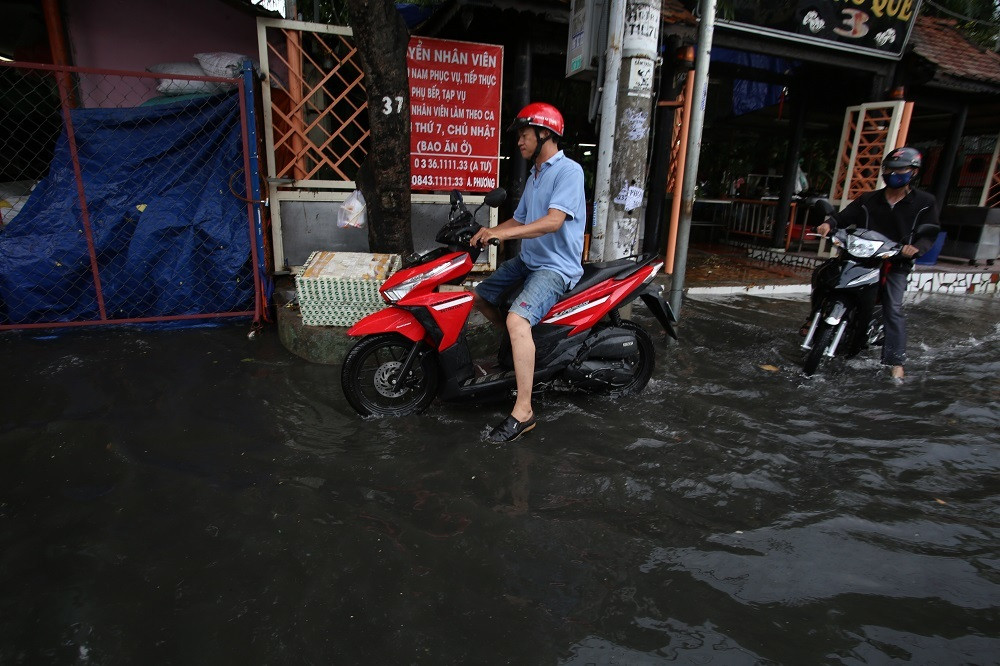 Nhiều người phải chạy sát vào lề đường để tránh nước ngập, xe chết máy. Hai bên đường, các cửa hiệu đóng cửa, kinh doanh 'đóng băng' vì ngập