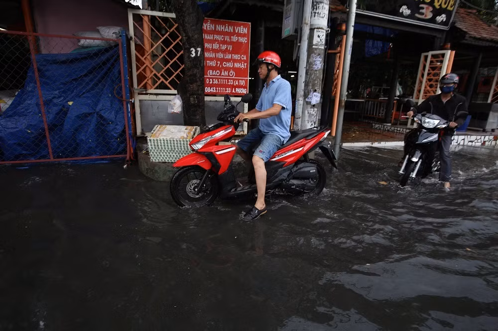 Nhiều người phải chạy sát vào lề đường để tránh nước ngập, xe chết máy. Hai bên đường, các cửa hiệu đóng cửa, kinh doanh 'đóng băng' vì ngập