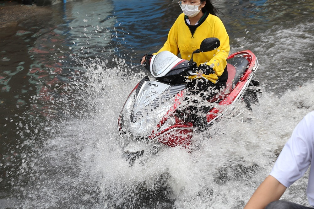 Nước ngập lênh láng, văng tung tóe khi người dân chạy xe qua