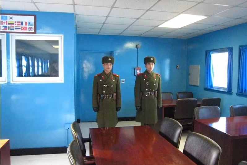 Lính Triều Tiên trong trang phục mùa đông bên trong một nhà xanh, họ đứng gác ở lối đi vào miền nam.