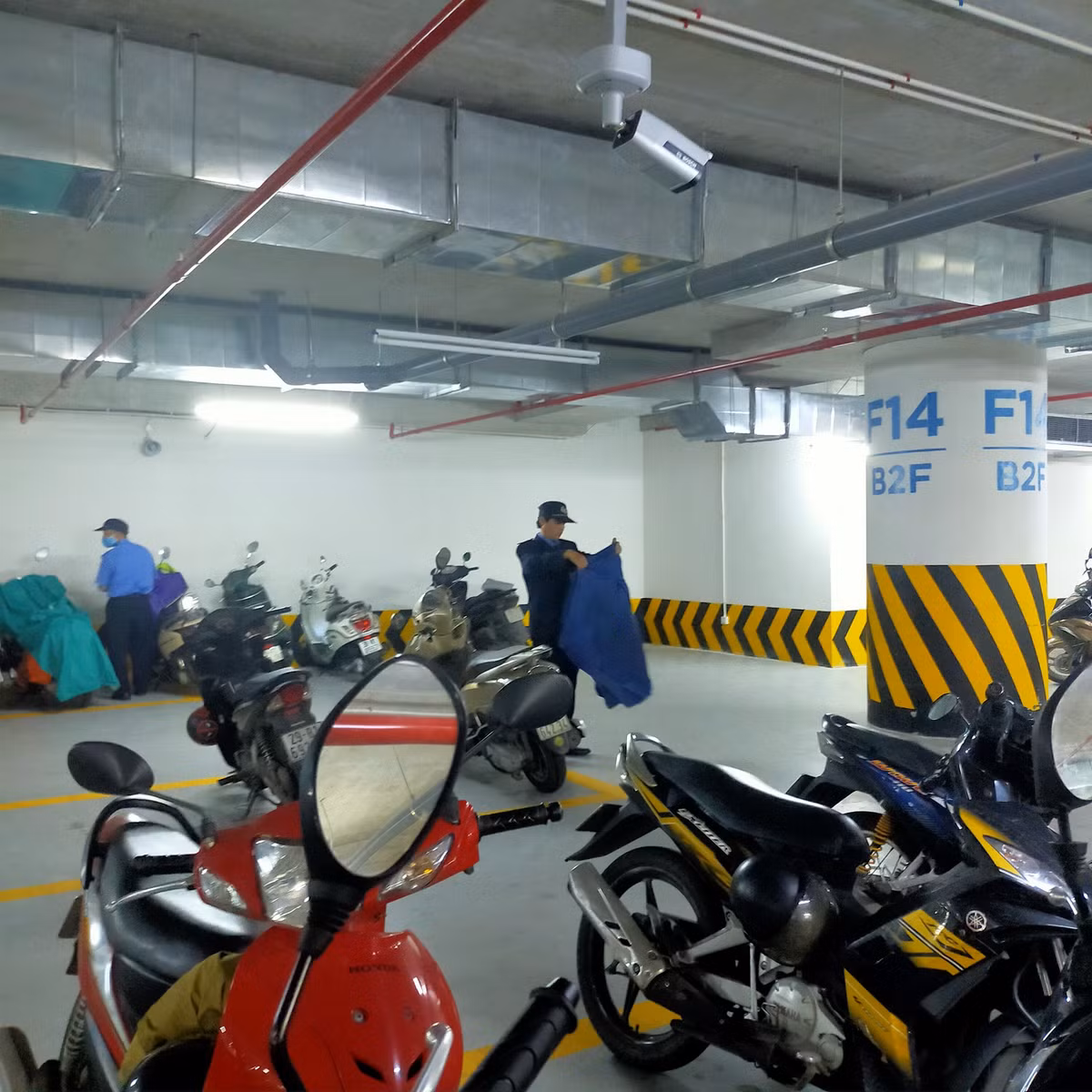 Không chỉ có nhiệm vụ trông xe, nhiều bác bảo vệ đã rất nhiệt tình khi gấp gọn luôn áo mưa cho người gửi xe một cách rất gọn gàng. Ảnh: Nguyễn Thị Minh Ngọc