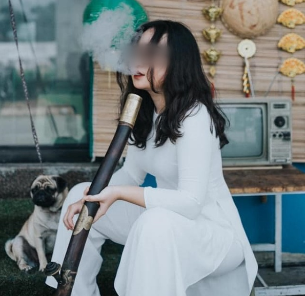 Mặc dù mặc trên người bộ áo dài truyền thống nhưng cô gái lại có hành động phản cảm nhả khói phì phèo thuốc lào.