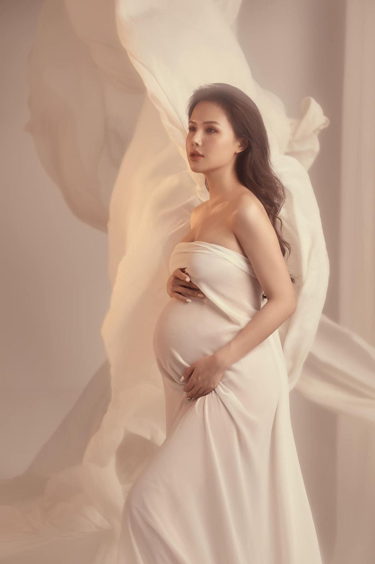 Quấn quanh người chiếc váy lụa mỏng, Phanh Lee làm tôn lên đường cong ý nghĩa của người phụ nữ trong giai đoạn mang thai.