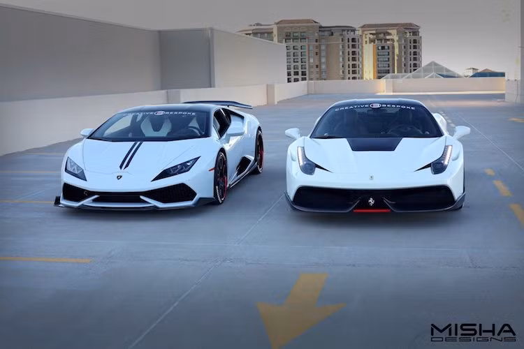 Không chỉ có chung màu sơn trắng và vòm mui màu đen, cả 2 chiếc siêu xe Ferrari 458 Italia và Lamborghini Huracan đều có điểm chung là được độ gói bodykit full sợi carbon của hãng Misha Design. Đây là một hãng độ ngoại thất siêu xe khá nổi tiếng tới từ Los Angeles, Mỹ và đã được thành lập từ năm 2004.