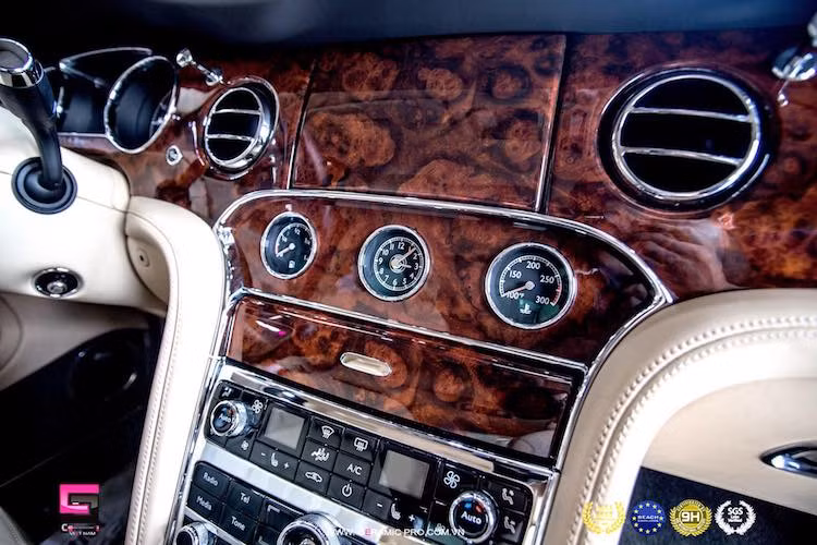 Màn hình của hệ thống thông tin giải trí nằm thẳng trên bảng táp-lô ốp gỗ với kích thước lớn, có thể ẩn đi và được điều khiển qua núm xoay trên bảng điều khiển trung tâm. Phía bên dưới là các đồng hồ báo giờ, báo xăng và nhiệt độ nước chạy cơ.