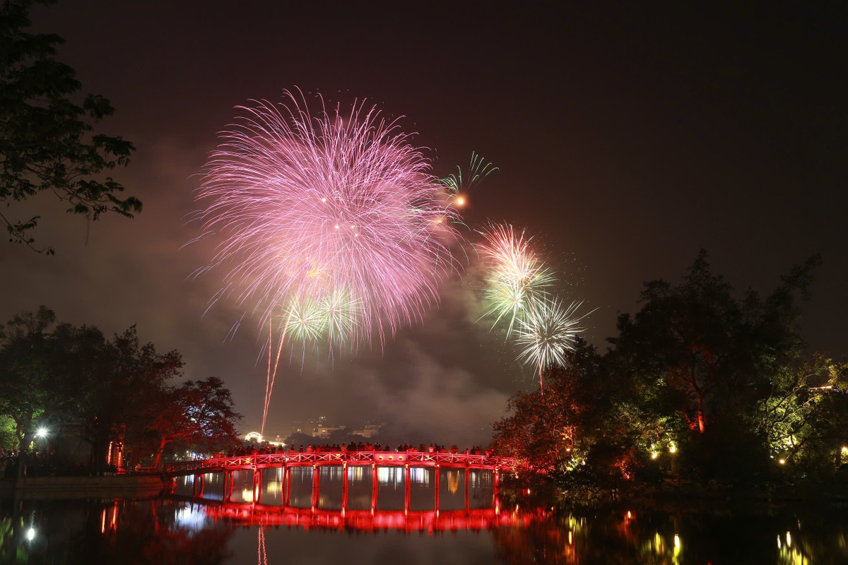 Pháo hoa tầm cao kết hợp tầm thấp, rực rỡ sắc màu soi bóng mặt hồ Gươm trên nền cầu Thê Húc đỏ thắm. 