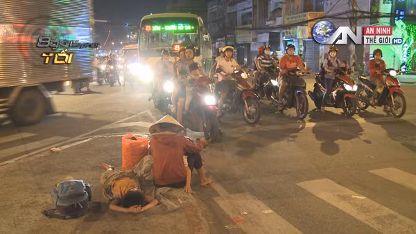 Một người mẹ mang theo cả hai người con đi ăn xin trên phố.