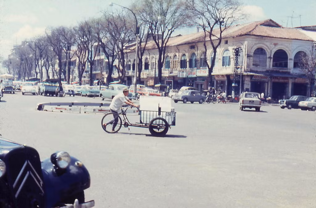 Người lái xe ba gác chở nước đá băng qua đại lộ Nguyễn Huệ.