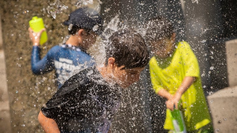 Bé Andrej, 10 tuổi, chơi đùa dưới vòi phun nước ở Vancouver ngày 28/6. Ảnh: CBC.