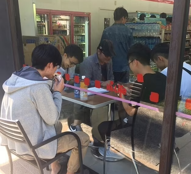 Người đàn ông không thể vào nhà hàng để ăn cùng bạn bè nên quyết định ngồi bên ngoài để có thể gần họ dù cách tấm cửa kính.