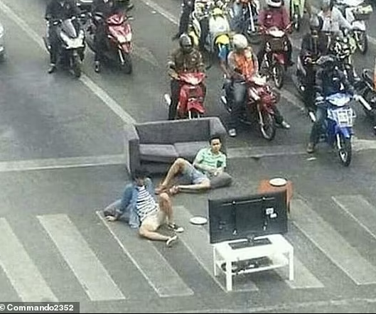 Hai người đàn ông mang TV ra giữa đường để xem dù giao thông đông đúc.