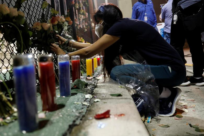 Người phụ nữ đặt hoa tưởng niệm các nạn nhân vụ sập chung cư 12 tầng tại Surfside, ngày 25/6.