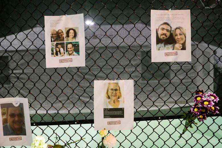 Ảnh của một số người mất tích trong vụ sập chung cư và hoa tưởng niệm được treo trên hàng rào ở Surfside ngày 25/6.