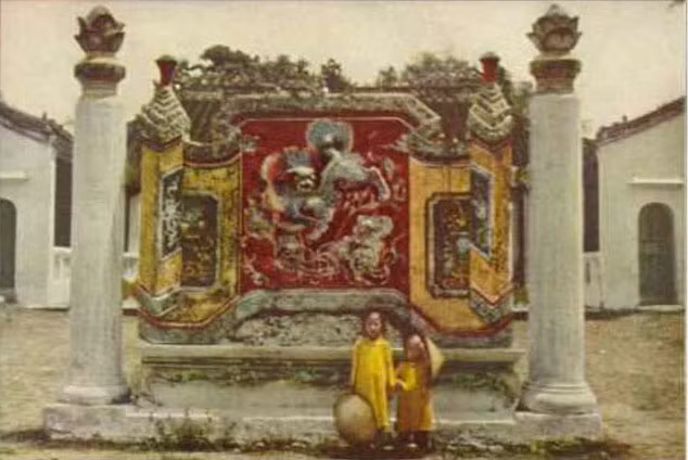 Hai em bé đứng trước bức bình phong của đình Cẩm Phô ở Hội An. Ảnh: National Geographic.