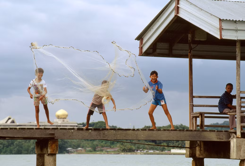 Trẻ em thả lưới bắt cá bên bờ sông Brunei. Ảnh: Gueorgui Pinkhassov.