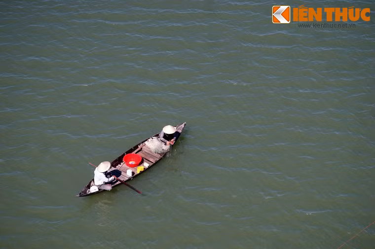 Hai người ngư dân thả lưới từ thuyền nan.