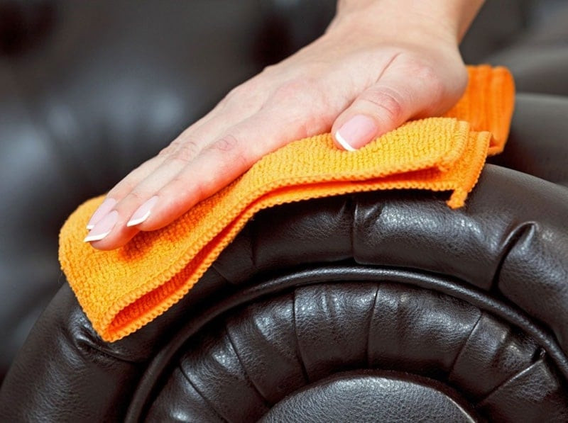 Với những vết bẩn đơn giản: Bạn pha nước và xà phòng vào một cái thau, sau đó nhúng một chiếc khăn mềm vào hỗn hợp này. Cuối cùng, vắt khô khăn và chà nhẹ lên vị trí cần làm sạch. Với những vết nấm mốc: Bạn pha 1/2 chén nước sạch cùng với 1/2 chén giấm ăn, sau đó nhúng một chiếc khăn mềm vào hỗn hợp này. Cuối cùng, vắt khô khăn và lau lên những vị trí bị nấm mốc. Với những vết cứng đầu (như màu mực, đồ ăn, đồ uống lâu ngày): Bạn dùng một chiếc khăn mềm, sau đó thấm một ít nước rửa chén vào rồi lau lên vết bẩn. Ảnh minh họa