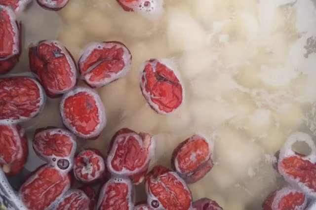 Rửa sạch táo đỏ, ngâm táo đỏ với nước ấm trong 5 phút. Cho vào hầm cùng hạt sen và củ năng. Khi táo đỏ nở tròn thì bắt đầu nêm đường phèn, muối vào. Ảnh Kingfood