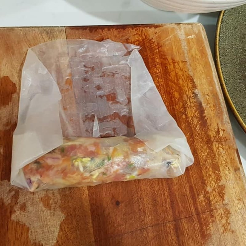  Cuốn nem: Trải 1 lá bánh đa nem ra thớt, rồi dùng khăn sạch nhúng nước, lau sơ qua mặt bánh cho mềm dễ cuốn. Tiếp tục, trải thêm 1/2 lá bánh đa nem vào giữa để tránh bị rách khi cuốn. Dùng muỗng múc lượng nhân bằng khoảng 3 ngón tay trải vào đầu lá nem. Sau đó cuộn chắc tay 2 vòng rồi dừng để gấp 2 đầu lá nem lại. Gấp xong thì tiếp tục cuốn đến khi hết lá nem. Cuối phần lá nem, bôi lòng trắng trứng vào để tạo độ dính. Sau đó vê tròn cuộn nem cho đẹp. Ảnh minh họa 