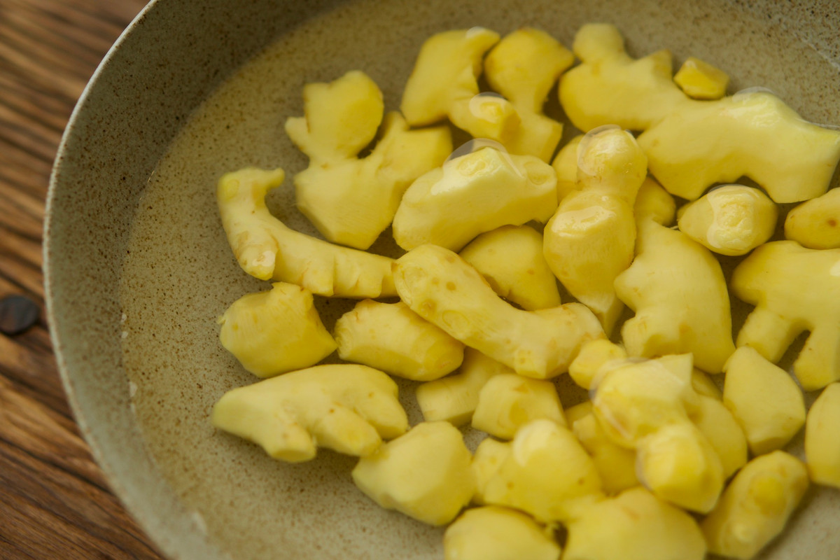 Gừng ngâm vào nước khoảng 20 - 30 phút rồi rửa sạch. Dùng dao nhỏ cạo sạch lớp vỏ bên ngoài, ngâm vào nước muối loãng. Ảnh Huệ Chip