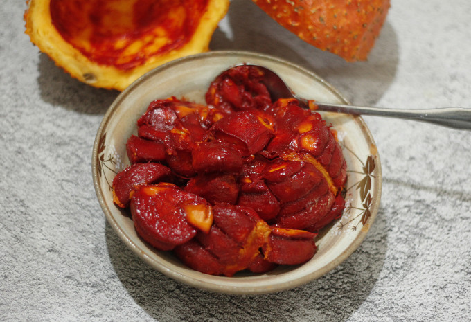 Gấc cắt đôi rồi gỡ lấy phần thịt gấc bên trong và bỏ hạt. Để gấc có thể dậy mùi thơm và giữ màu đỏ bắt mắt, cho 15ml rượu gạo vào trộn đều. Ảnh minh họa