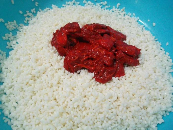 Trộn gấc và gạo nếp qua sơ chế. Sau khi trộn xong thì để trong vòng 1 tiếng để gạo ngấm màu của gấc. Ảnh minh họa