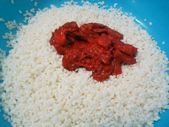 Trộn gấc và gạo nếp qua sơ chế. Sau khi trộn xong thì để trong vòng 1 tiếng để gạo ngấm màu của gấc. Ảnh minh họa