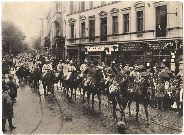 Sĩ quan và binh lính Đức cưỡi ngựa di chuyển trên đường phố ở châu Âu.