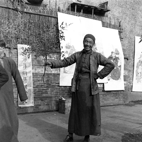 Một người đàn ông bán cây cảnh và tranh trên đường phố Trung Quốc những năm 1900.