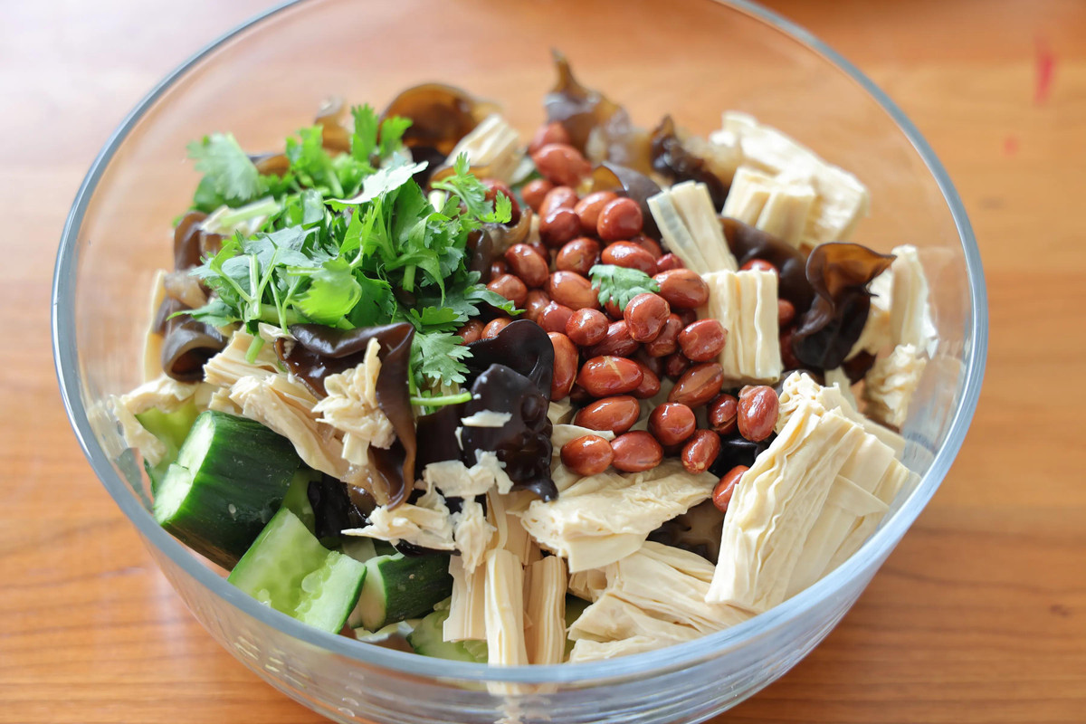 Bước 6: Cho nấm mộc nhĩ, mì váng đậu đã ráo nước và dưa chuột vào chung một bát, sau đó đổ lạc vừa chiên và rau mùi vào.