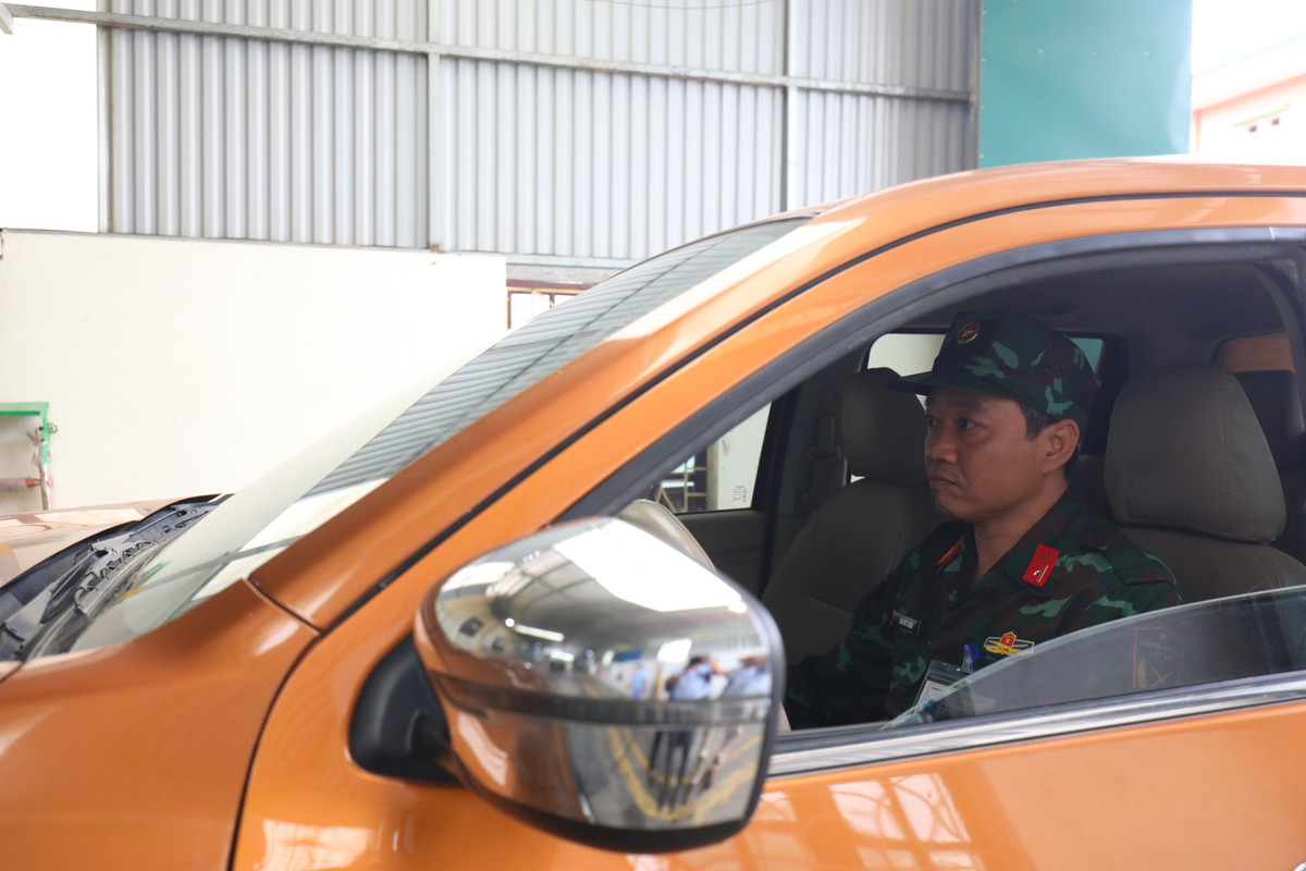 Phía trong dây chuyền, 1 kiểm định viên quân sự khác được phân công kiểm tra gầm, hỗ trợ việc di chuyển xe trên dây chuyền để thực hiện công đoạn kiểm tra đèn xe, trong khi kiểm định viên quân sự còn lại phụ trách việc chụp ảnh lưu trữ tem kiểm định xe lên hệ thống cơ sở dữ liệu và thực hiện việc dán tem kiểm định giúp người dân.