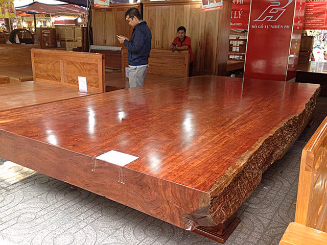  Sập gỗ cẩm đỏ 2,5 tỷ đồng Chiếc sập gỗ cẩm đỏ nguyên khối giá 2,5 tỷ đồng có đường kính lên đến 2,2m, dài 4,4m, bề dày 24,5cm, nặng tới 3,2 tấn. Chiếc sập này rất "độc" bởi đường vân và ánh màu của gỗ không chê vào đâu được. Ảnh: Vietnamnet.