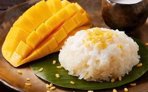 Mùa hè ở Thái Lan không chỉ được biết đến với cái nóng oi ả mà còn là thời điểm lý tưởng để thưởng thức một món tráng miệng nổi tiếng: xôi xoài (mango sticky rice). Đây là món ăn dân dã nhưng lại được yêu thích nồng nhiệt, không chỉ bởi hương vị tuyệt vời mà còn vì sự kết hợp tinh tế giữa các nguyên liệu tự nhiên. Ảnh MIA