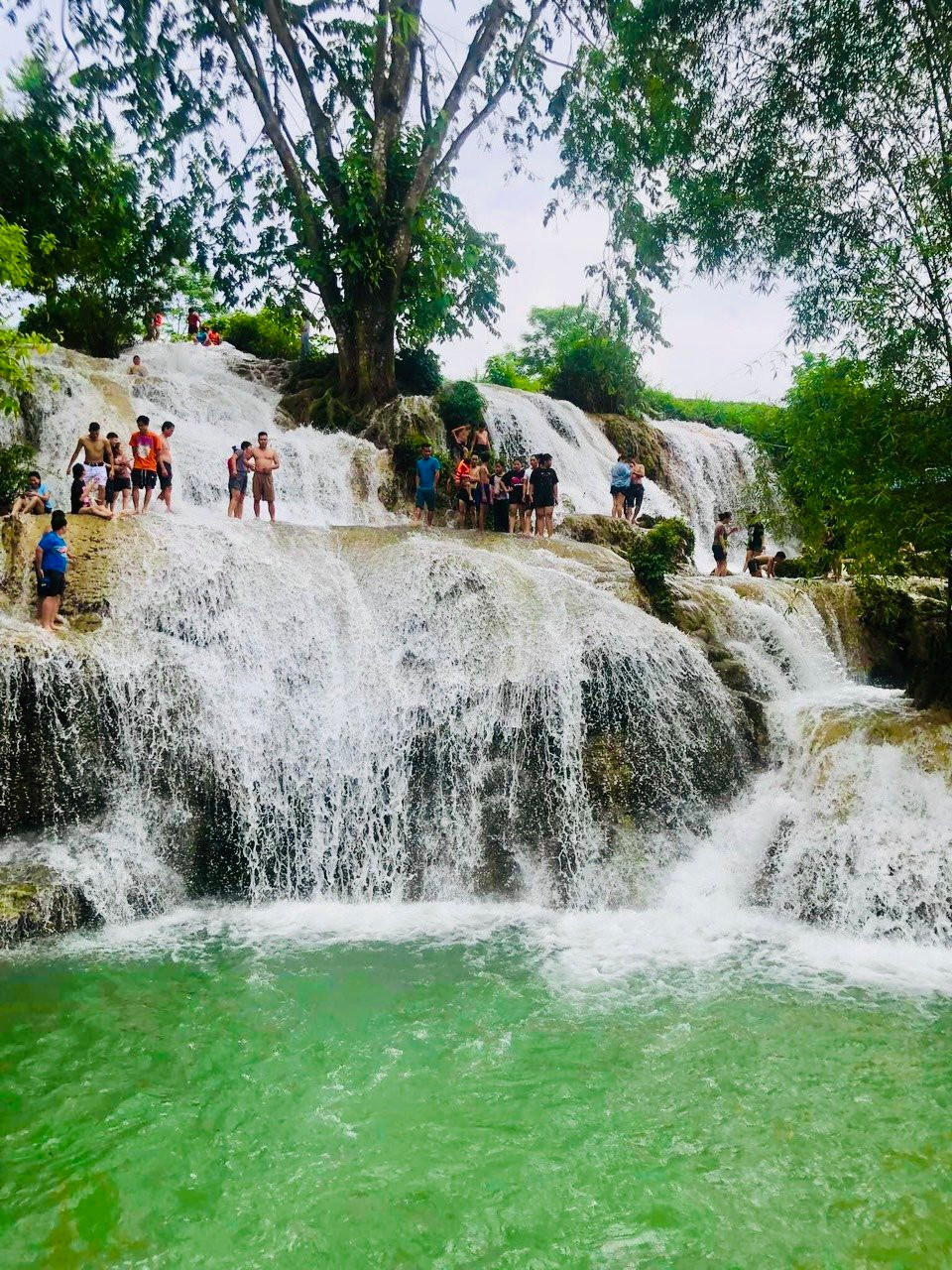 Dưới chân thác là hồ nước tự nhiên rộng rãi, nơi du khách có thể thoải mái tắm mát, bơi lội hoặc đơn giản là ngồi thư giãn giữa thiên nhiên. Mặt nước lấp lánh ánh nắng, được bao bọc bởi đá núi và cây rừng, tạo nên không gian vừa hoang sơ, vừa thơ mộng. Ảnh Mai Mai
