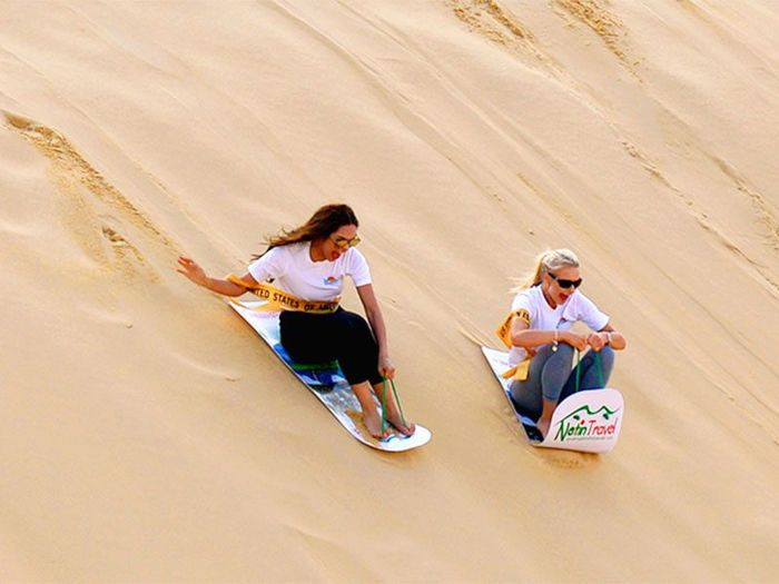 Với một tấm ván nhựa đơn giản, du khách có thể ngồi hoặc nằm để thả mình trượt dài theo các dốc cát cao, tận hưởng cảm giác mạnh giữa thiên nhiên mênh mông. Ảnh dulichPhanThiet