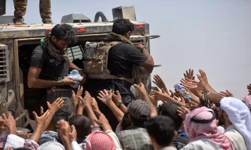 Lực lượng an ninh Iraq phân phát nước uống cho nhiều người dân Iraq ở vùng ngoại ô Al-Shirqat hôm 26/6.