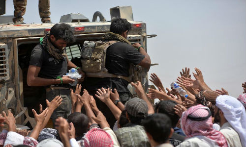 Lực lượng an ninh Iraq phân phát nước uống cho nhiều người dân Iraq ở vùng ngoại ô Al-Shirqat hôm 26/6.