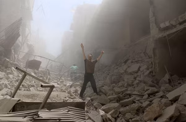 Một binh sĩ chính phủ Syria đứng trong tòa nhà đổ nát ở lối vào thành cổ Palmyra ngày 24/3/2016.