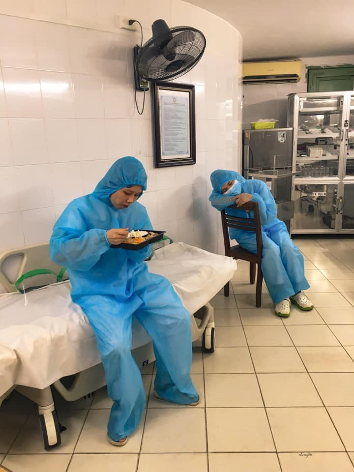 Các nhân viên y tế ở Bạch Mai người tranh thủ ăn cơm, người chợp mắt sau những giờ làm việc vất vả.