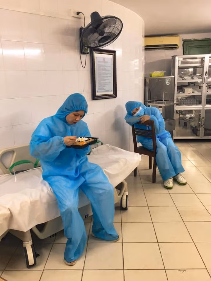 Các nhân viên y tế ở Bạch Mai người tranh thủ ăn cơm, người chợp mắt sau những giờ làm việc vất vả.